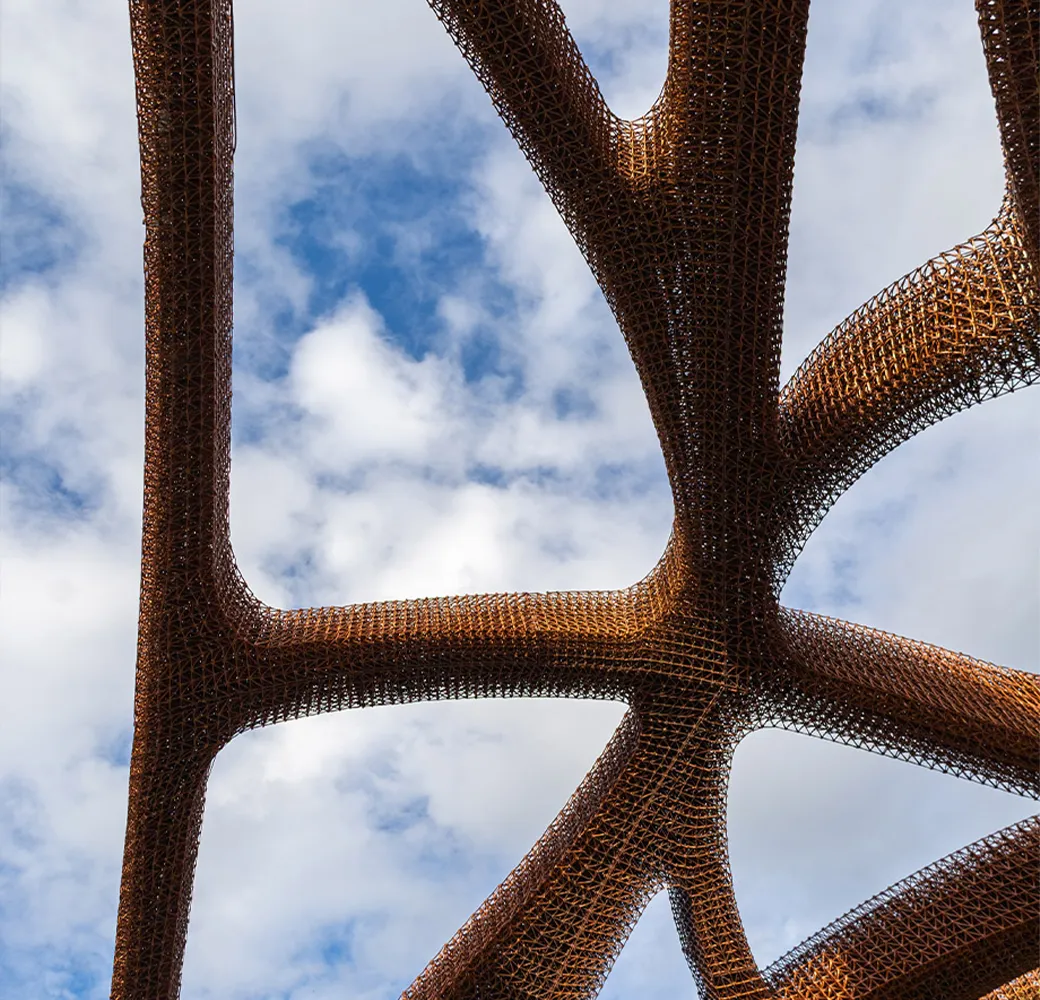 Copper lattice canopy against a cloudy sky
